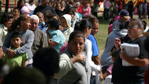 Migrant workers line up at the U.S. border to apply for farm work. Two temporary foreign workers who were sexually harassed at an Ontario fish-processing plant have been awarded a total of $200,000. (Gary Kazanjian/Associated Press)